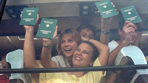 Glücklich halten Übersiedler aus der DDR, die am 11. September 1989 in einem Reisebus über Österreich in Bayern eintreffen, ihre bundesdeutschen Reisepässe in die Fensterscheibe des Busses. | Bild: picture-alliance/dpa