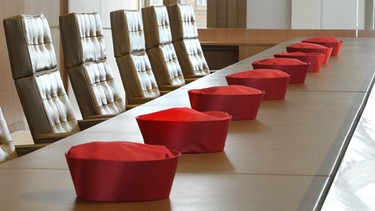 Die Barette der Verfassungsrichter liegen auf dem Tisch in einem Verhandlungssaal des Bundesverfassungsgerichts in Karlsruhe | Bild: picture-alliance/dpa