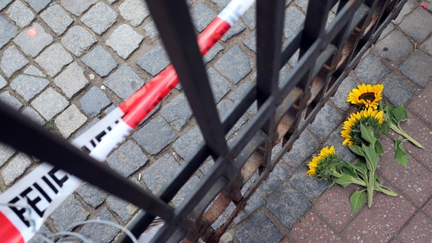 Polizeiabperrung und Sonnenblumen liegen auf Gehwegpflaster | Bild: imago images