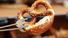 Eine Breze wird in München (Bayern) in einer Bäckerei mit einer Zange gehalten.  | Bild: picture-alliance/dpa/Tobias Hase