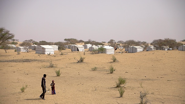 Zwei Flüchtlinge laufen im Tschad an der Grenze zu Nigeria vor einem Flüchtlingscamp durch den Sand. | Bild: picture-alliance/dpa/Kristin Palitza