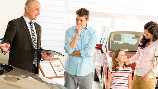 Car dealer offering a vehicle to young couple | Bild: picture-alliance/dpa