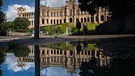 Der Sitz des bayerischen Landtags, das Maximilianeum, spiegelt sich nach einem starken Regenguss in einer Pfütze.  | Bild: dpa-Bildfunk/Peter Kneffel
