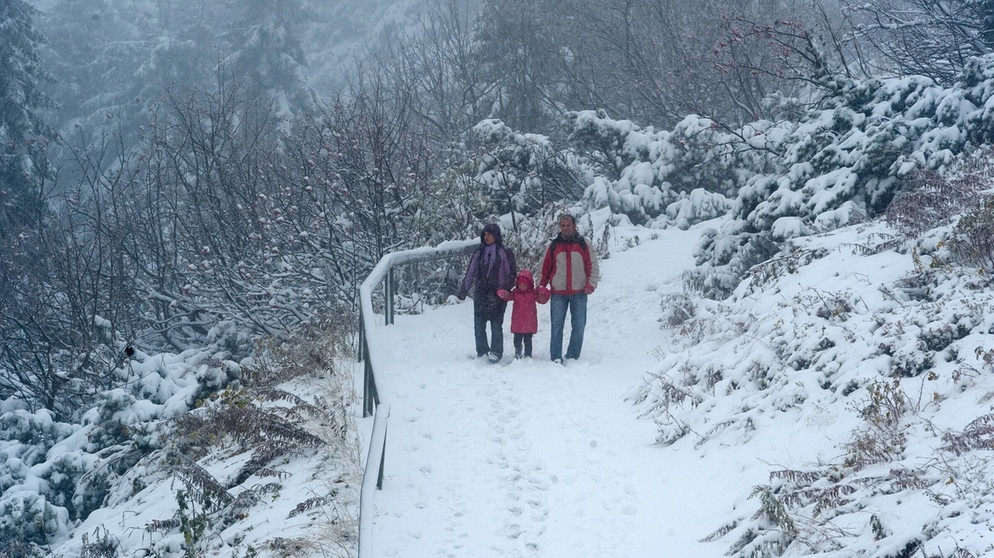 Eine Familie wandert am Großen Arber auf einem mit Schnee bedeckten Weg | Bild: picture-alliance/dpa