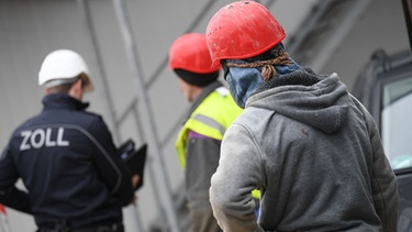 Ein Beamter des Zoll kontrolliert Bauarbeiter | Bild: picture-alliance/dpa/Arne Dedert