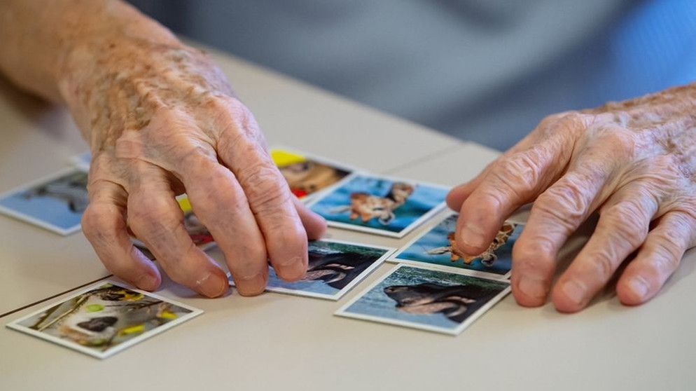 Hände einer alten Frau, die Memory-Karten nebeneinander legt. | Bild: dpa-Bildfunk/Sven Hoppe