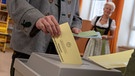 Männer und Frauen in regionaler Tracht bei der Kommunalwahl  | Bild: picture alliance/Peter Kneffel/dpa