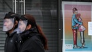 27.03.2020, Irland, Dublin: Ein Paar mit Gesichtsschutz-Visier gehen an einem Poster mit dem Titel «The Spirit of Love» (Der Geist der Liebe) des Künstlers Jawgem in einem Schaufenster in der O'Connell Straße vorbei. Foto: Brian Lawless/PA Wire/dpa +++ dpa-Bildfunk +++ | Bild:  Foto: Brian Lawless/PA Wire/dpa 