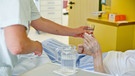Ein Pfleger reicht ein Glas Wasser ans Bett | Bild: dpa-Bildfunk/Daniel Karmann