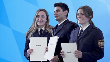 Annelie (li), Hasan und Marina (re) freuen sich nach dem Abschluss der Polizeischule über ihre Urkunden, | Bild: BR
