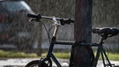 Ein Fahrrad steht im Regen und wird gleichzeitig von der Sonne angestrahlt (Symbolbild). | Bild: picture alliance/dpa | Frank Rumpenhorst