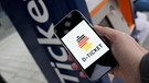 Eine Hand hält ein Smartphone auf dem ein Deutschland-Piktogramm mit der Unterschrift "D-TICKET" zu sehen ist. Dahinter ein Fahrkartenautomat. | Bild: picture alliance / Flashpic | Jens Krick