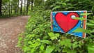 Neben einem Wanderweg steht ein Schild mit einem roten Herz als Symbol für die kardiovaskuläre Teststrecke. | Bild: Birgit Böhm / Technische Universität München