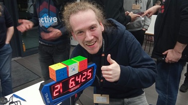 Jakob Schöley hat in Schweinfurt einen Weltrekord geknackt: Er löste drei Zauberwürfel jonglierend in nur zwei Minuten und sechs Sekunden.  | Bild: BR/Ralph Wege