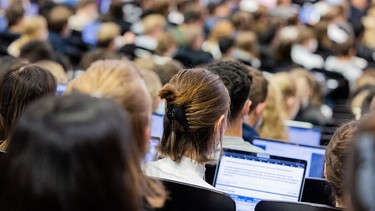 Studierende sitzen in einem Hörsaal. Vor ihnen stehen Laptopts.  | Bild: dpa-Bildfunk/Rolf Vennenbernd