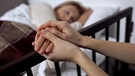 Patient liegt im Bett, jemand hält seine Hand | Bild: Colourbox