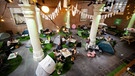 Gäste essen vor ihrem Zelt in einer ehemaligen Kirche. | Bild: picture alliance / ANP | Robin van Lonkhuijsen