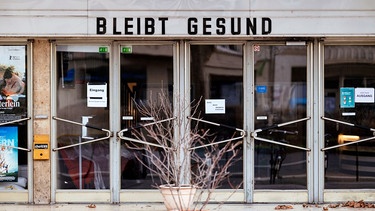 Symbolbild: Ein geschlossenes Kino, auf der Anzeigetafel die Buchstaben "Bleibt gesund" | Bild: picture alliance/Geisler-Fotopress/Christoph Hardt