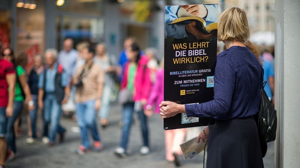 Mitglieder der Religionsgemeinschaft "Zeugen Jehovas" stehen am 27.07.2015 am Viktualienmarkt in München. | Bild: picture alliance / dpa | Matthias Balk