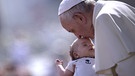 Der Papst küsst bei einer Generalaudienz auf dem Petersplatz ein Baby | Bild: picture alliance / Stefano Spaziani 