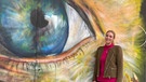 Gudrun Stifter steht vor einem großen Graffiti, das ein Auge abbildet | Bild: BR/Agnieszka Schneider