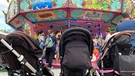 Drei Kinderwägen stehen vor einem Kettenkarussell | Bild: BR/Elisabeth Möst