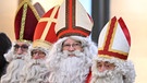 Mitglieder der Nikolausgilde Friedrichshafen stehen als Nikoläuse verkleidet während eines Gottesdienstes in der katholischen Kirche «Zum guten Hirten» | Bild: dpa-Bildfunk/Felix Kästle