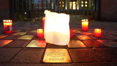 Kerzen stehen an Stolpersteinen bei der Gedenkfeier an die Pogromnacht.  | Bild: dpa-Bildfunk/Marcus Brandt