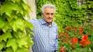 Älterer Herr in einem blühenden Garten: Der Schriftsteller John Irving | Bild: dpa/ picture alliance