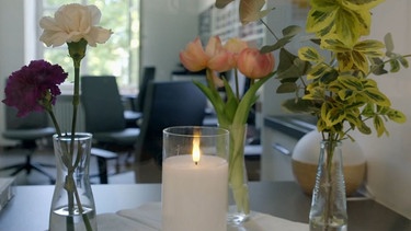 Auf einem Tisch steht eine Kerze und ein Blumenstrauß | Bild: Bayerischer Rundfunk 2024