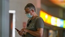 Ein Mann mit Maske an seinem Handy. Das Gerät könnte auch bei der Eindämmung des Coronavirus helfen. | Bild: dpa/Iván Terrón