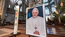 Ein gerahmtes Foto von Papst Benedikt XVI. steht im Regensburger Dom.  | Bild: dpa-Bildfunk/Armin Weigel
