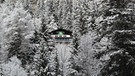 Berghütte umgeben von verschneitem Wald | Bild: BR/Alex Brutscher