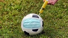 Fußball mit Corona-Schutzmaske bekommt eine Spritze | Bild: picture-alliance/dpa