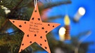 Weihnachtsbaum mit einem Stern, auf dem jemand die Aufschrift "Ich wünsche mir eine glückliche Familie" angebracht hat. | Bild: pa/dpa/Martin Schutt