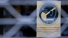 Ein Schild, das auf die Schutzmaskenpflicht in einem Geschäft hinweist, hängt hinter einem Gitter. | Bild: dpa-Bildfunk