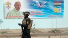Ein Soldat in Bagdad vor einem Plakat mit Papst Franziskus | Bild: dpa-Bildfunk/Khalid Mohammed