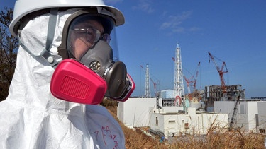 Besucher mit Atemmaske vor dem Atomkraftwerk Fukushima | Bild: picture-alliance/dpa/AP Yoshikazu Tsuno