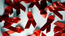 Rote Aids-Schleifen liegen auf einem Tisch. | Bild: dpa-Bildfunk/Jens Kalaene