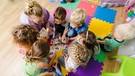 Eine Erzieherin mit einer Gruppe Kinder in einer Kindertagesstätte. | Bild: stock.adobe.com/oksix