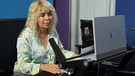 Journalistin Olga Lubiana sitzt im Radio Studio vor ihrem Mikrofon und ihrem Bildschirm und führt ein Interview | Bild: Rebekka Preuß