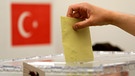 Archivbild: 07.06.2018: Nordrhein-Westfalen, Hürth: Ein Stimmzettel wird im türkischen Generalkunsulat in eine Urne geworfen.  | Bild: picture alliance/dpa | Oliver Berg