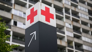 Symbolbild: Ein Schild mit einem roten Kreuz weist den Weg zur Notaufnahme eines Krankenhauses.  | Bild: dpa-Bildfunk/Julian Stratenschulte