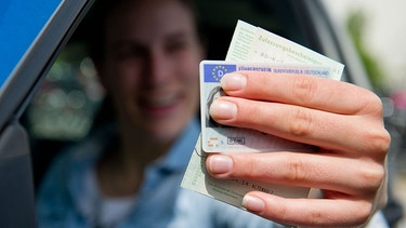 Eine Frau hält Führerschein und Fahrzeugschein in die Kamera | Bild: picture alliance / dpa Themendienst | Inga Kjer