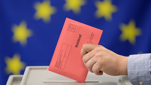 Eine Stimmabgabe für das Europäische Parlament, eine Hand wirft einen Wahlbriefumschlag in eine Urne (gestellte Szene) | Bild: dpa-Bildfunk/Ralf Hirschberger