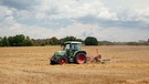 Ein Bauer der mit seinem Traktor das Heu auf seinem Feld wendet. | Bild: BR/Herbert Ebner