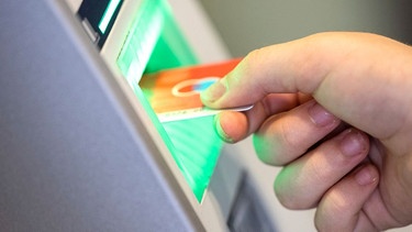 Jemand steckt eine EC-Karte in einen Geldautomaten, um Bargeld abzuheben. | Bild: dpa-Bildfunk/Thomas Banneyer