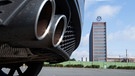 Auspuffrohre eines Volkswagen, fotografiert mit dem Markenhochhaus am VW Werk Wolfsburg. | Bild: dpa-Bildfunk/Julian Stratenschulte