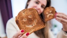 Eine junge Frau hält zwei Scheiben Toastbrot mit eingeritzten Gesichtern in den Händen. | Bild: pa / dpa / Christin Klose