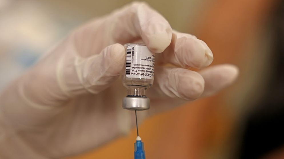Ein Dosis Covid-19-Impfstoff wird auf eine Spritze aufgezogen; eine Hand mit Gummihandschuh hält das Fläschchen mit dem Impfstoff | Bild: Menahem KAHANA / AFP